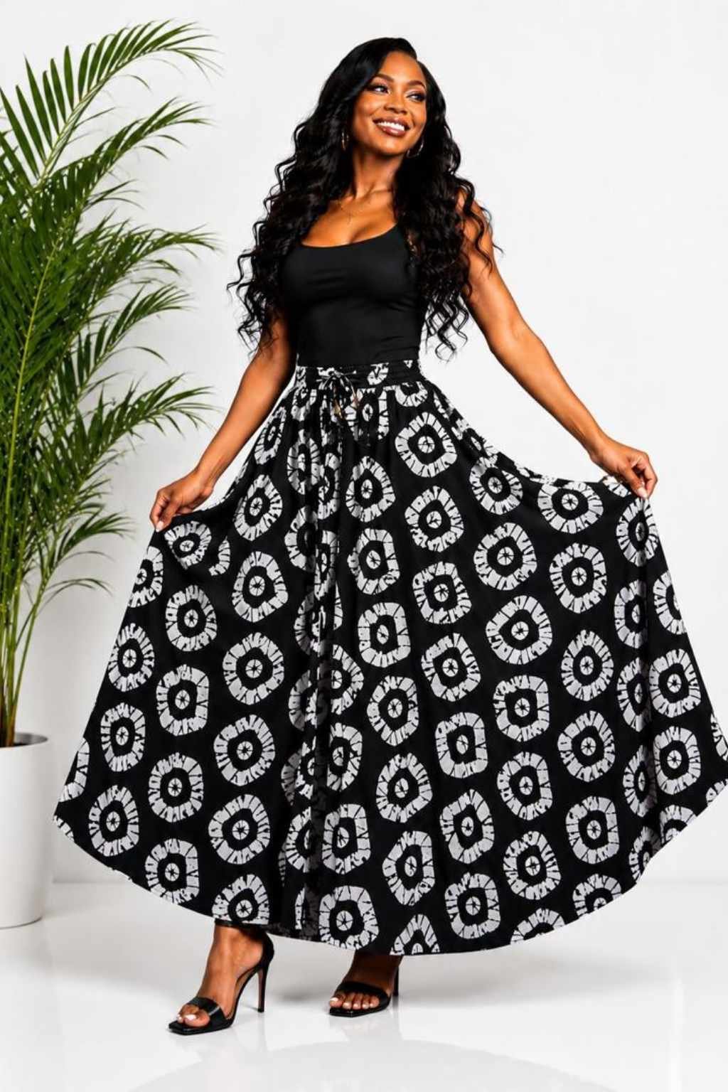 Woman wearing a black and white batik circle African print high-waisted pleated maxi skirt