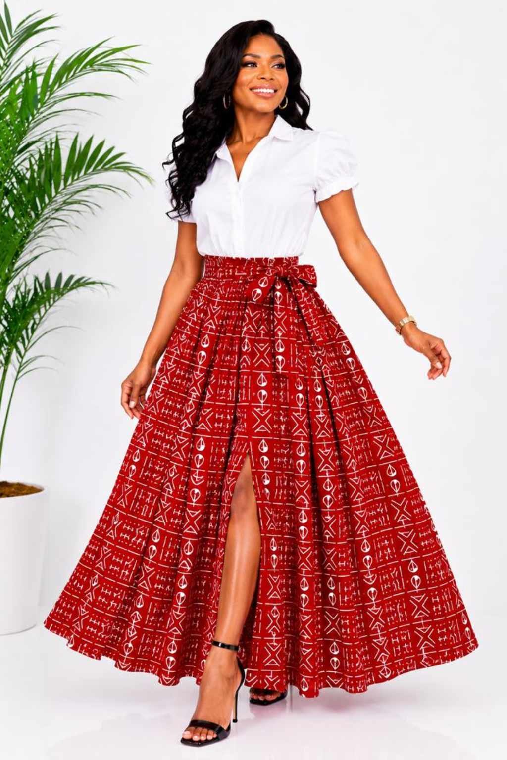 Woman wearing a red and white mudcloth bogolan African print high-waisted pleated maxi skirt