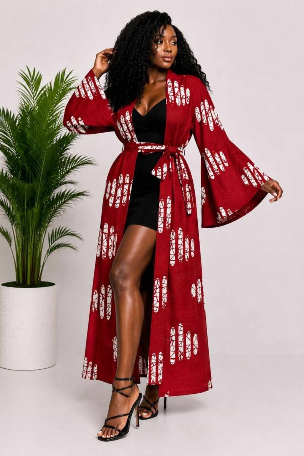 Woman wearing a deep red and white batik African print long kimono duster with bell sleeves
