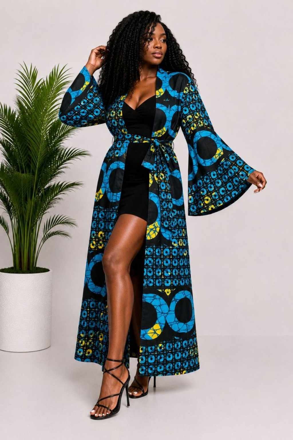 Woman wearing a blue, black and yellow circular African print long kimono duster with bell sleeves