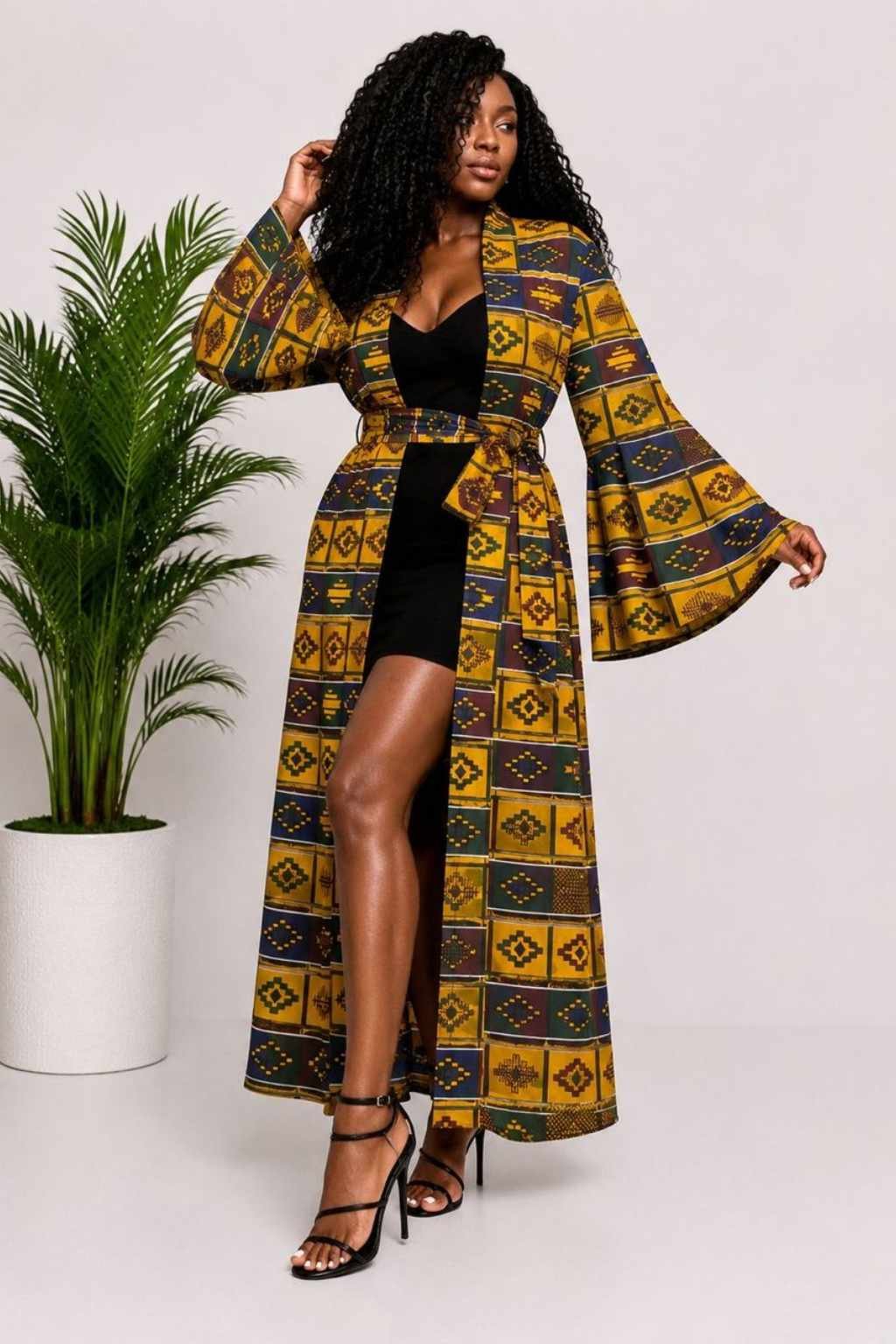 Woman wearing a mustard gold kente-style geometric African print long kimono duster with bell sleeves
