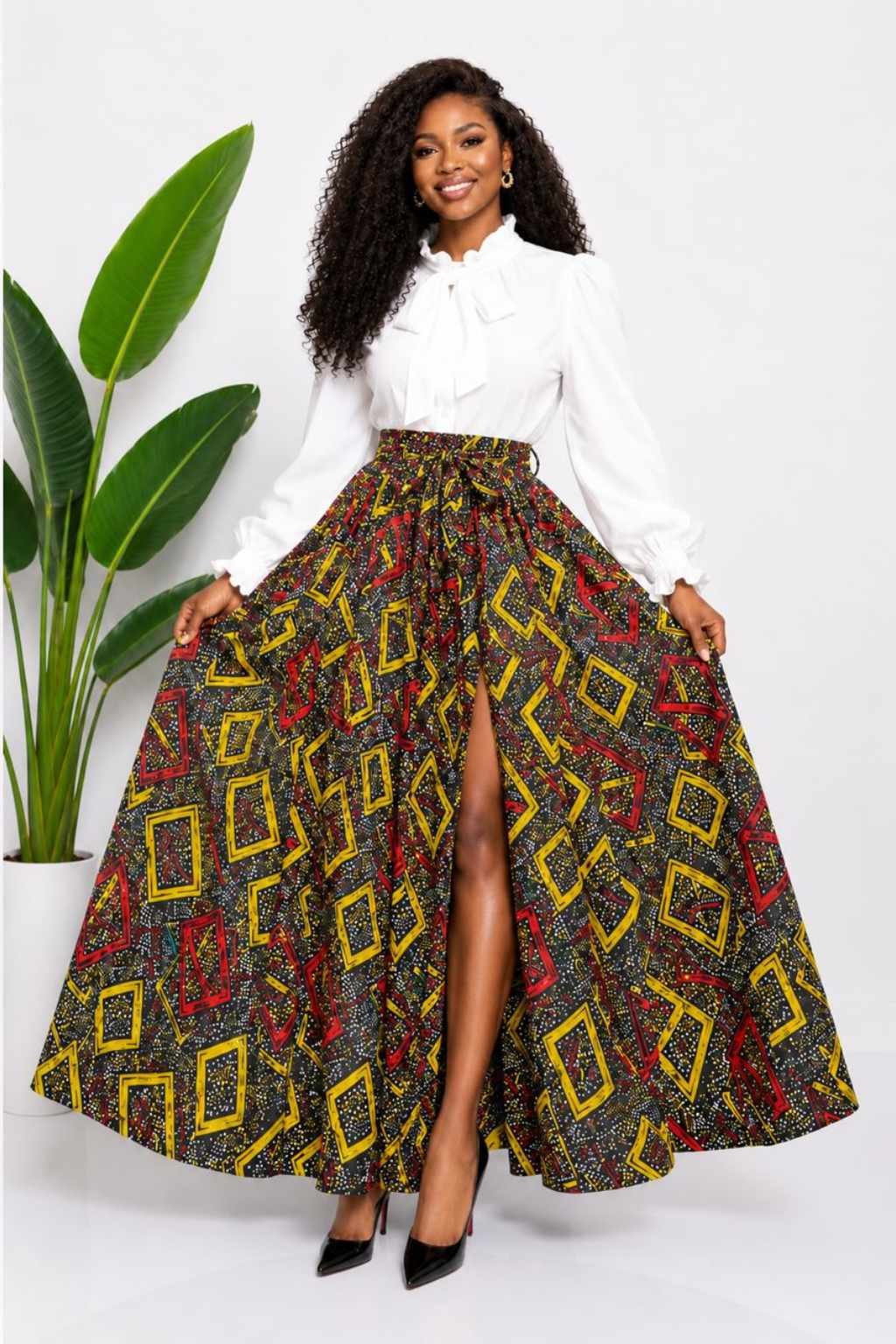 Woman wearing a black, red and yellow geometric African print high-waisted pleated maxi skirt