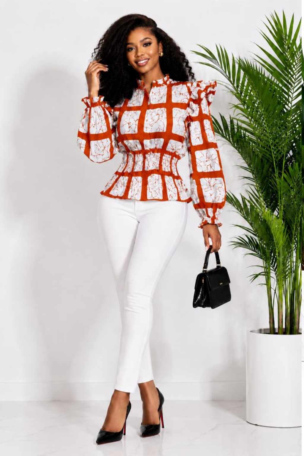 Woman wearing a rust orange and cream windowpane check African print ruffle peplum top