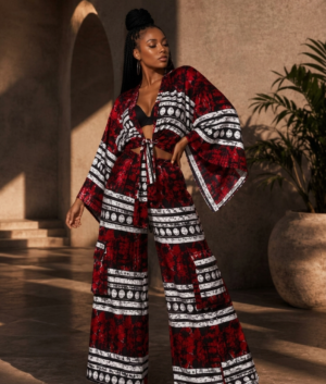 Woman modeling a luxury red and black African print two-piece co-ord set with a wide-sleeve tie-front kimono top and matching high-waisted wide-leg palazzo pants.