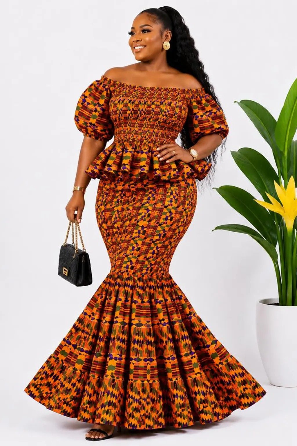 Woman wearing an orange kente African print off-shoulder peplum mermaid maxi dress