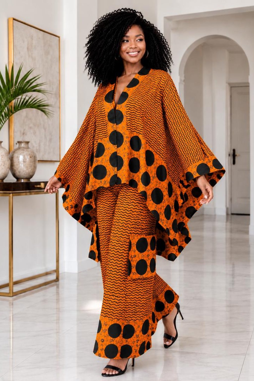 A Woman Wearing A Terracotta & Onyx Polka Dot Asymmetric Poncho And Wide-Leg Cargo Trousers Set.