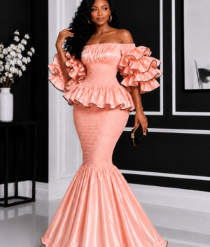 A Woman Wearing An Elastic Luminous Peach Rose Gold Smocked Peplum Top & Ruffle Mermaid Maxi Skirt Set.