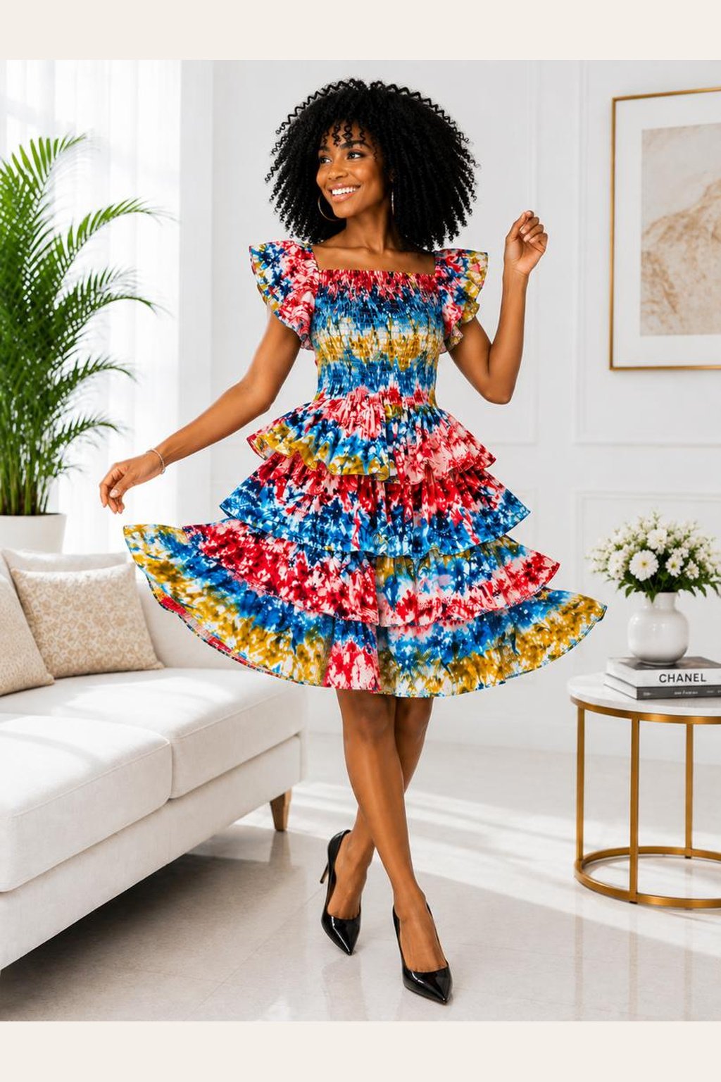 A Woman Wearing A Zaria Multi-Tiered Ruffle Cocktail Dress – Vibrant Kaleidoscope Tie-Dye Print with Flutter Sleeves.