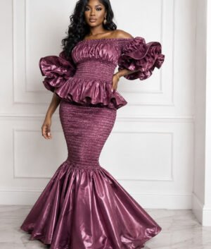 Woman Wearing A Zuri Metallic Smocked Mermaid Dress – Deep Plum Satin Two-Piece Gown with Dramatic Tiered Ruffles.