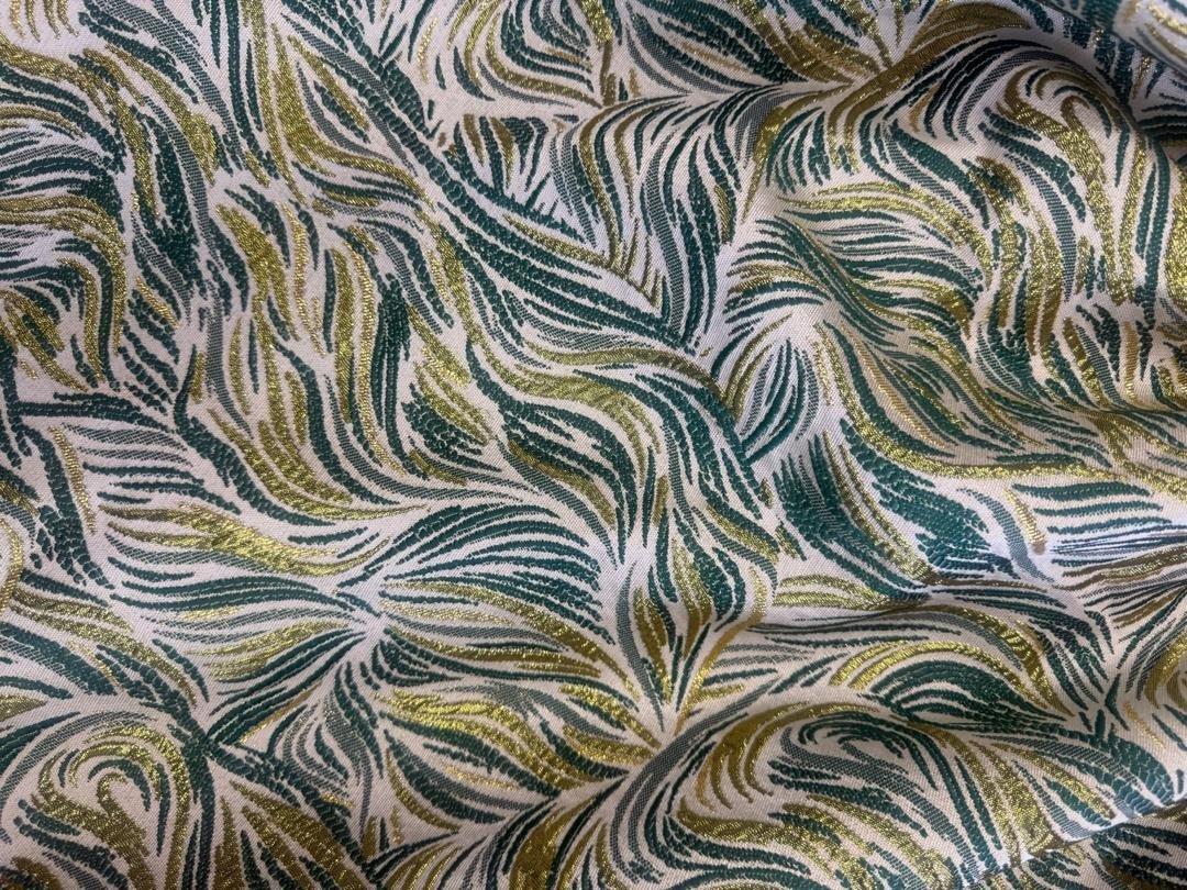 Emerald Elastic Green & Gold Metallic Jacquard Smocked Peplum Mermaid Gown. 5 A Woman Wearing An Emerald Elastic Green & Gold Metallic Jacquard Smocked Peplum Mermaid Gown.