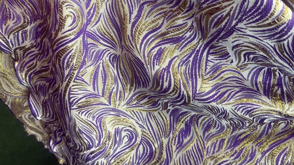 Imperial Elastic Purple & Gold Metallic Jacquard Smocked Peplum Mermaid Gown, 5 A Woman Wearing An Imperial Elastic Purple & Gold Metallic Jacquard Smocked Peplum Mermaid Gown.